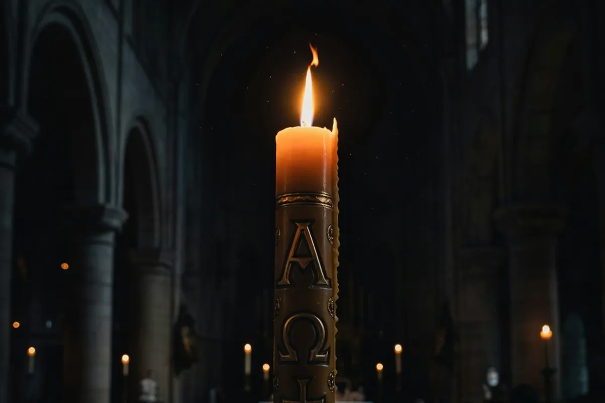Cierge pascal allumé lors de la Vigile pascale dans une église plongée dans l'obscurité